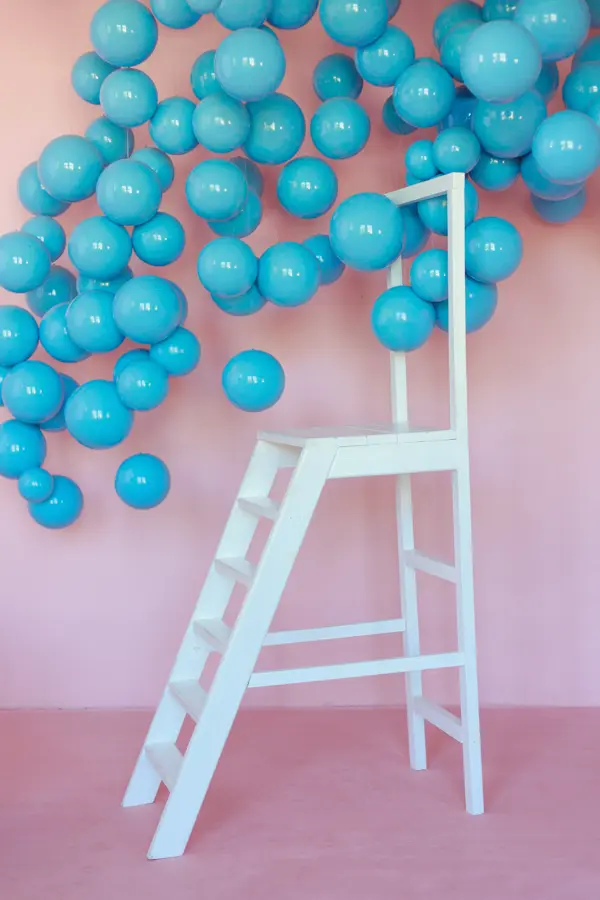 Pembe duvar önünde turkuaz balonlar ve beyaz bir merdiven